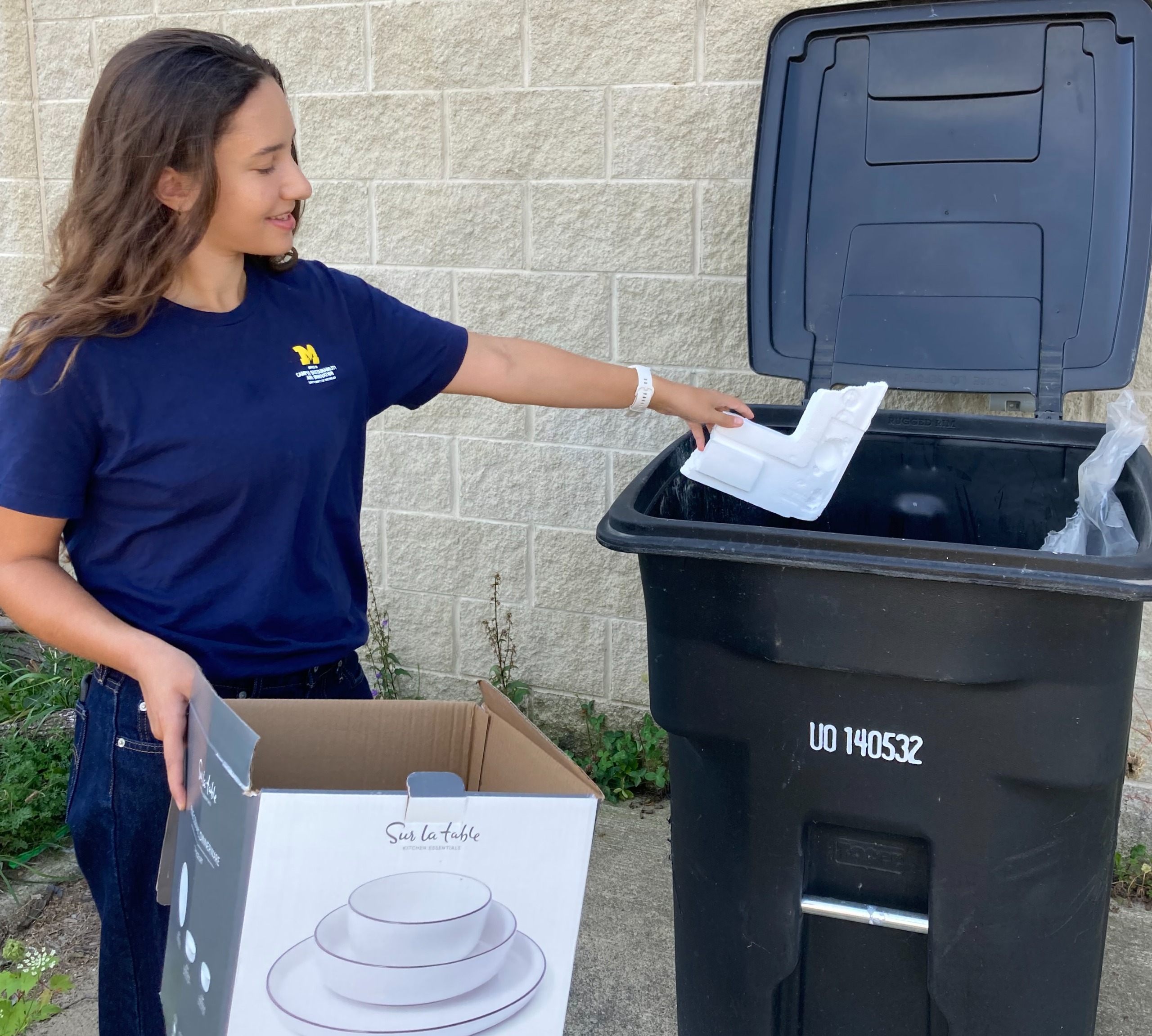 Woman removing styrofoam from box and putting it in the trash. 
