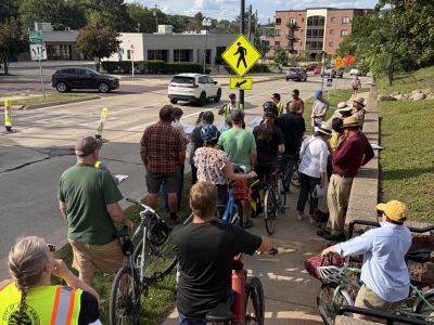 People gathered on sidewalk listening to a presentation on Division Street.