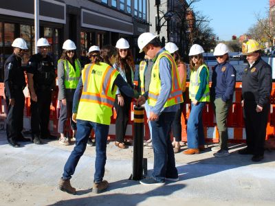 People watching two individuals pulling a bollard out of the ground