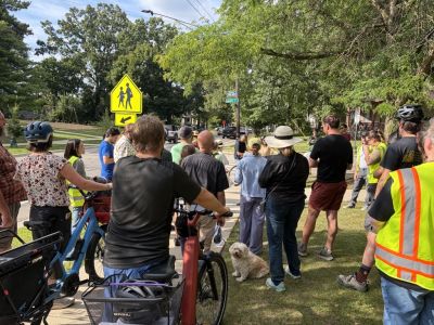People gathered on sidewalk listening to a presentation on Division Street.
